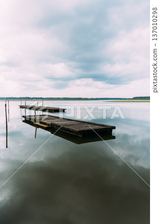 Lake of Soustons reflecting a cloudy sky and wooden docks Lake of Soustons reflecting a cloudy sky and wooden docks 137010298