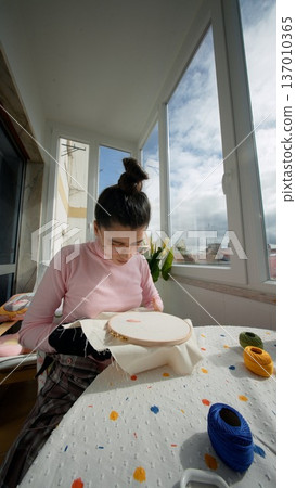 Young lady concentrating on detailed embroidery in natural sunshine 137010365