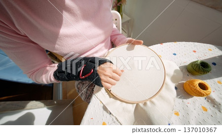 Woman inspecting embroidery hoop for pattern alignment 137010367