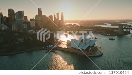 Amazing sunset over Sydney Opera House modern skyscrapers city skyline and Sydney Harbor Bridge, boats sailing calm water. Australia main landmark. Travel destination background. Aerial drone panorama 137010434