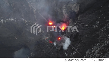 Mountain Yasur volcano on Tanna Island, Vanuatu, actively erupting, showing molten lava explosions and thick plumes of smoke rising from a deep, rocky crater. Natural phenomena. Aerial view drone shot 137010846