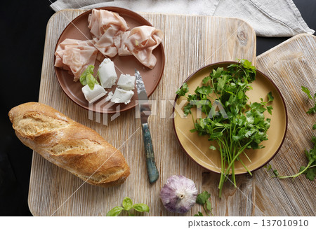 High-quality farm food on wooden cutting board. Top view. Flat lay photo. Soft goat cheese on bread, basil and mortadella sandwich. Italian tradition cuisine. High-quality farm food on wooden cutting board. Top view. Flat lay photo. Soft goat cheese on bread, basil and mortadella sandwich. Italian tradition cuisine. 137010910