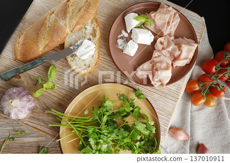 High-quality farm food on wooden cutting board. Top view. Flat lay photo. Soft goat cheese on bread, basil and mortadella sandwich. Italian tradition cuisine. High-quality farm food on wooden cutting board. Top view. Flat lay photo. Soft goat cheese on bread, basil and mortadella sandwich. Italian tradition cuisine. 137010911