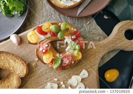 Round bruschetta with red and yellow cherry tomatoes and goat cheese on oak wooden board. Farm produce, crusty bread. Food and healthy eating. Round bruschetta with red and yellow cherry tomatoes and goat cheese on oak wooden board. Farm produce, crusty bread. Food and healthy eating. 137010920