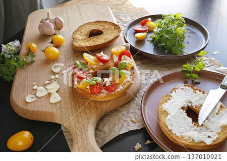 Round bruschetta with red and yellow cherry tomatoes and goat cheese on oak wooden board. Farm produce, crusty bread. Food and healthy eating. Round bruschetta with red and yellow cherry tomatoes and goat cheese on oak wooden board. Farm produce, crusty bread. Food and healthy eating. 137010921