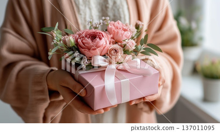 Woman holding pink gift box decorated with bouquet of roses and ribbon bow. Celebration and romantic surprise concept 137011095