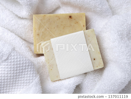 Mockup of beige solid soap bar with blank paper label on white bath towel, personal care packaging Mockup of beige solid soap bar with blank paper label on white bath towel, personal care packaging 137011119