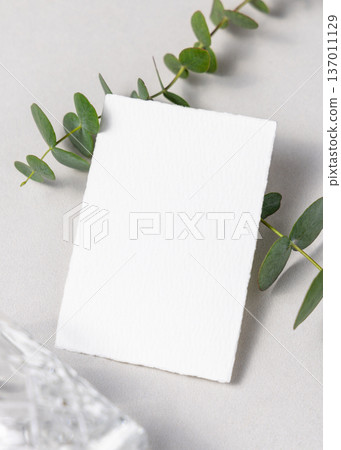 Mockup of blank card near green eucalyptus branche sand crystal glasses. Presentation template 137011129