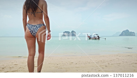 Thailand, Koh Lanta: sexy young woman in bikini walking sandy tropical beach and swim turquoise sea water, longtail boat with limestone islands in background. Travel, holiday, relax, summer vacation Thailand, Koh Lanta: sexy young woman in bikini walking sandy tropical beach and swim turquoise sea water, longtail boat with limestone islands in background. Travel, holiday, relax, summer vacation 137011216