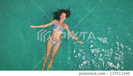 Beautiful young woman enjoy tranquility, floating on her back in clear turquoise ocean water, relaxing under sun during tropical vacation to Koh Lanta, Thailand. Aerial top down panorama zoom out Beautiful young woman enjoy tranquility, floating on her back in clear turquoise ocean water, relaxing under sun during tropical vacation to Koh Lanta, Thailand. Aerial top down panorama zoom out 137011240