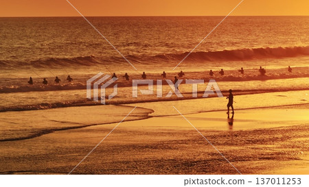 Bright orange sunset with fishermen people silhouettes cast lines into rolling ocean waves at Bali tropical beach, warm golden light, tranquil tropical seascape evoking leisure, tradition and calm Bright orange sunset with fishermen people silhouettes cast lines into rolling ocean waves at Bali tropical beach, warm golden light, tranquil tropical seascape evoking leisure, tradition and calm 137011253