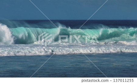 Powerful turquoise ocean wave cresting and breaking off Bali coast, white foam and spray capturing raw motion and energy of surf and tropical seascape on a clear day. Natural background, slow motion Powerful turquoise ocean wave cresting and breaking off Bali coast, white foam and spray capturing raw motion and energy of surf and tropical seascape on a clear day. Natural background, slow motion 137011255