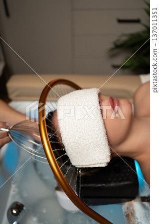 Client relaxing during a wellness head spa with water treatment and scalp massage for hair care in a beauty salon Client relaxing during a wellness head spa with water treatment and scalp massage for hair care in a beauty salon 137011351