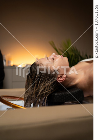 Woman lying back, receiving hair treatment and wash in a salon basin, creating a moment of blissful relaxation Woman lying back, receiving hair treatment and wash in a salon basin, creating a moment of blissful relaxation 137011358