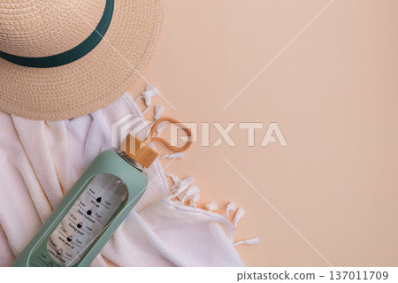 Beach hat, water bottle, and towel on a light background. 137011709