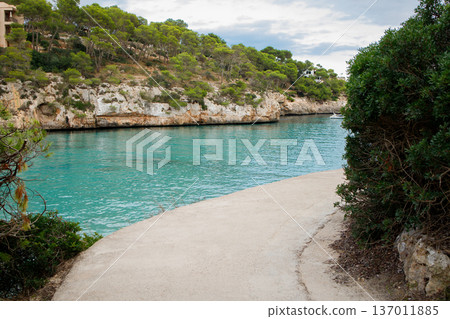 Narrow path over the sea leading to the beach with crystal clear turquoise water. Summer dream vacation on Mallorca, Spain. Nature of Balearic islands. 137011885