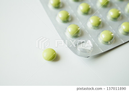 Green pills in a blister pack on white background. Healthcare and medicine, pharmaceutical industry. Green pills in a blister pack on white background. Healthcare and medicine, pharmaceutical industry. 137011890