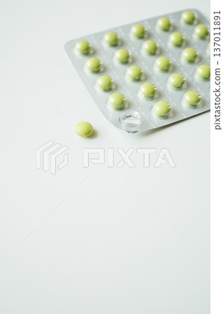 Green pills in a blister pack on white background. Healthcare and medicine, pharmaceutical industry. 137011891
