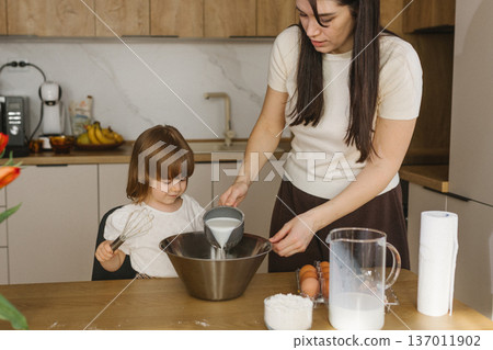Mother and little daughter baking together in modern kitchen at home, happy family cooking and spending time together 137011902