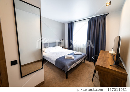 Modern minimalist hotel bedroom interior with double bed workspace and natural daylight Modern minimalist hotel bedroom interior with double bed workspace and natural daylight 137011981