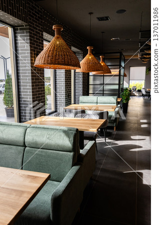 Stylish modern restaurant interior with cozy seating and natural light from large windows Stylish modern restaurant interior with cozy seating and natural light from large windows 137011986