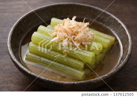 在一張寧靜的木桌上，擺放著精緻的菜餚，包括用優雅的日式餐具盛裝的蜂斗菜沙拉和鰹魚片。 137012505