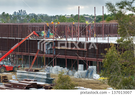 Workers assembling metal frame building at industrial construction site. Housing development in America. Real estate market in the USA Workers assembling metal frame building at industrial construction site. Housing development in America. Real estate market in the USA 137013007