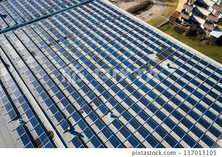 Aerial view of many photo voltaic solar panels mounted of industrial building roof. Aerial view of many photo voltaic solar panels mounted of industrial building roof. 137013105