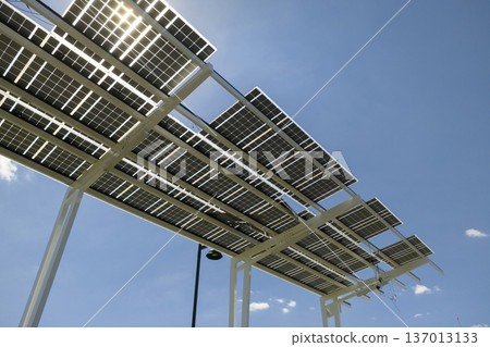 Failing of photovoltaic technology integrated in urban infrastructure. Hurricane wind damage to solar panels installed as shade roof over parking lot for parked electric cars 137013133