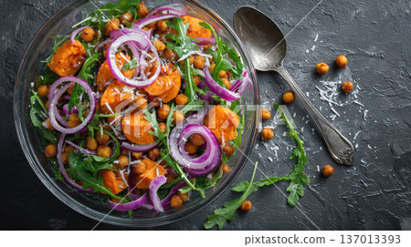 Hearty Sweet Potato and Chickpea Salad Nutritious Plant-Based Meal with Fresh Arugula, Sharp Red Onion Rings, and Parmesan Cheese on a Dark Rustic Stone Background Healthy Vegan Vegetarian Diet 137013393