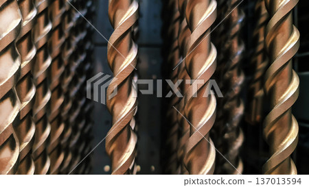 Close-up of twisted metal rods or drill bits arranged vertically in a row. The black and white photography with shallow depth of field emphasizes the metal texture, rhythmic forms 137013594