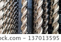 Close-up of twisted metal rods or drill bits arranged vertically in a row. The black and white photography with shallow depth of field emphasizes the metal texture, rhythmic forms 137013595