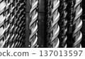 Close-up of twisted metal rods or drill bits arranged vertically in a row. The black and white photography with shallow depth of field emphasizes the metal texture, rhythmic forms 137013597