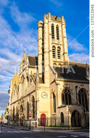 Scenic sunny street view of the historic stone architecture, gothic windows, and prominent bell tower of the Saint-Nicolas-des-Champs church in Paris, France. Scenic sunny street view of the historic stone architecture, gothic windows, and prominent bell tower of the Saint-Nicolas-des-Champs church in Paris, France. 137013848