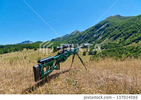 Bolt-Action Sniper Rifle With Scope And Bipod On Dry Grass Overlooking Mountain Valley Bolt-Action Sniper Rifle With Scope And Bipod On Dry Grass Overlooking Mountain Valley 137014088