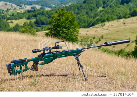 Bolt-Action Sniper Rifle With Scope and Suppressor On Bipod In Open Grassland Hunting Field 137014104