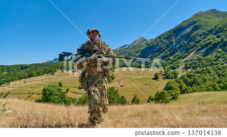 Sniper In Ghillie Suit Walking Through Mountain Meadow With Rifle Tactical Gear And Camouflage Sniper In Ghillie Suit Walking Through Mountain Meadow With Rifle Tactical Gear And Camouflage 137014136