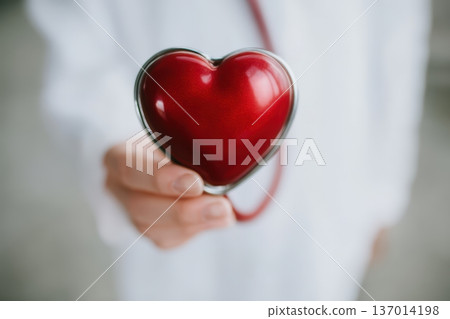 A Hand Holding a Heart Symbol Accompanied by a Stethoscope, Signifying Care and Compassion 137014198