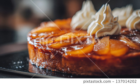 Decadent French Tarte Tatin: Close-Up of a Glazed, Caramelized Pear Tart Topped with Beautiful Swirls of Fresh Whipped Cream, Showcasing a Luxurious and Delicious Dessert in a Softly Lit, Dark Setting Decadent French Tarte Tatin: Close-Up of a Glazed, Caramelized Pear Tart Topped with Beautiful Swirls of Fresh Whipped Cream, Showcasing a Luxurious and Delicious Dessert in a Softly Lit, Dark Setting 137014202