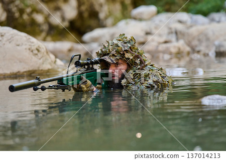 Camouflaged Sniper Soldier Wading in Water With Scoped Rifle Concealed by Ghillie Suit Camouflaged Sniper Soldier Wading in Water With Scoped Rifle Concealed by Ghillie Suit 137014213