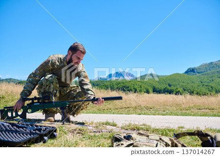 Military Sniper Soldier Preparing Rifle in Open Field Landscape 137014267
