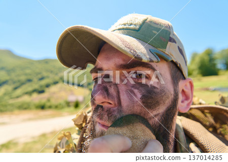 Soldier Applying Camouflage Face Paint During Outdoor Military Training In Field 137014285