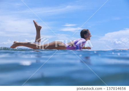 Youthful Female Surfer Smiling Peacefully On Her Board With Tropical Background Youthful Female Surfer Smiling Peacefully On Her Board With Tropical Background 137014656
