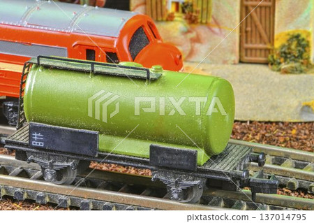 Vintage model train tanker car with detailed markings and a red locomotive in the background. A close-up view of a miniature green tanker car on a model railway track, featuring authentic historical Vintage model train tanker car with detailed markings and a red locomotive in the background. A close-up view of a miniature green tanker car on a model railway track, featuring authentic historical 137014795