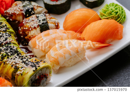 Closeup sushi set with salmon shrimp nigiri and rolls served on white plate 137015970