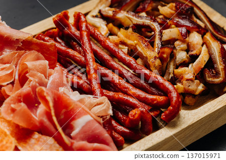 Closeup of cured meats and smoked sausages on wooden board gourmet snack assortment Closeup of cured meats and smoked sausages on wooden board gourmet snack assortment 137015971