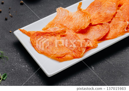 Crispy dried meat chips served on white plate gourmet protein snack closeup 137015983