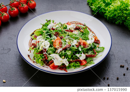 Fresh green salad with tomatoes dried tomatoes and creamy dressing on plate Fresh green salad with tomatoes dried tomatoes and creamy dressing on plate 137015990