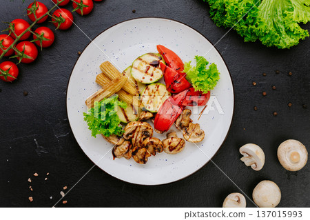 Grilled vegetables with mushrooms zucchini and pepper served on plate over dark background 137015993