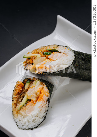 Hand roll sushi with salmon cucumber and rice wrapped in nori on white plate Hand roll sushi with salmon cucumber and rice wrapped in nori on white plate 137016003